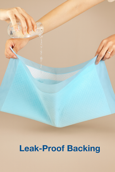 Light blue underwear with a hand holding it and another hand pouring water, on a beige background.