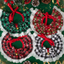 Four decorative Christmas wreaths with red ribbons on a green background.
