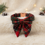 Red plaid bow tie and collar set on a fluffy surface with Christmas decorations.